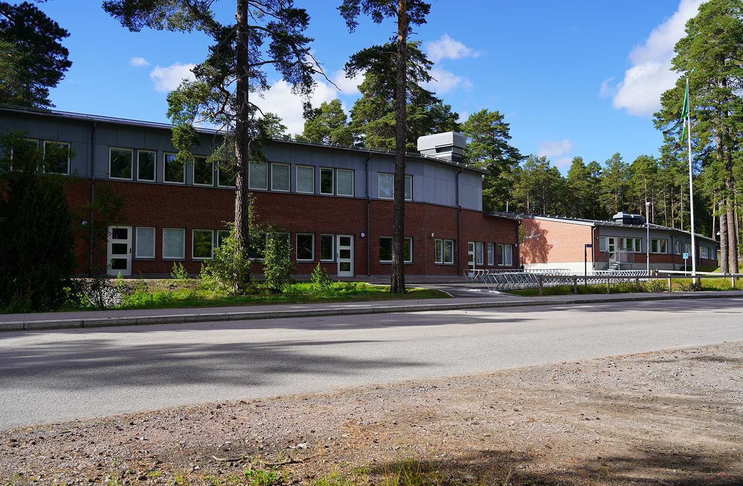 Tvåvånings byggnad i tegel, framför går en asfalterad väg.