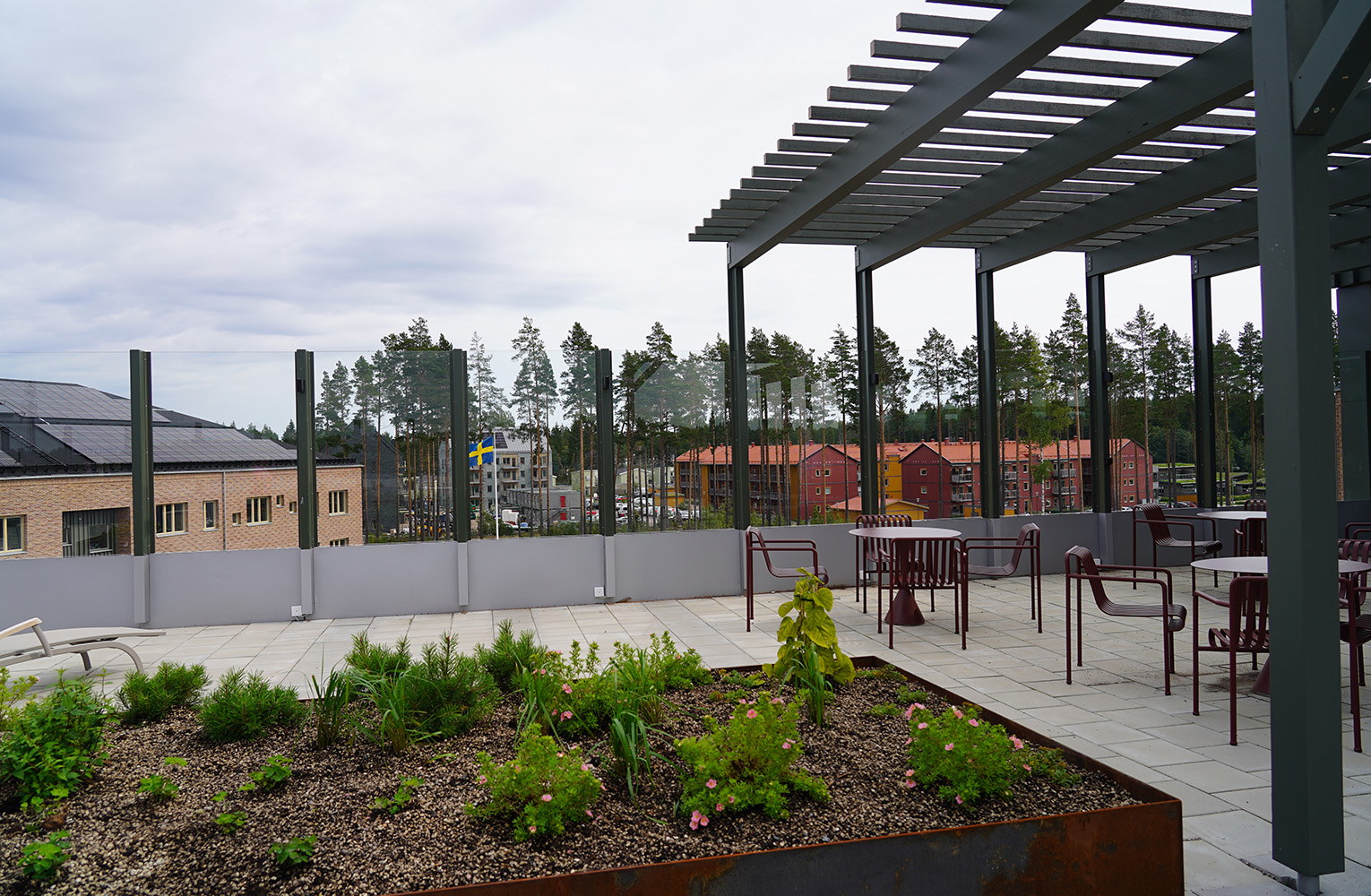 Sittplatser under pergola och planteringar på takterrass.