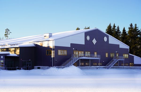 Gaveln på ett hus med mörka och ljusa partier på fasaden samt konstverk i form av snöstjärnor. Snötäckt mark.