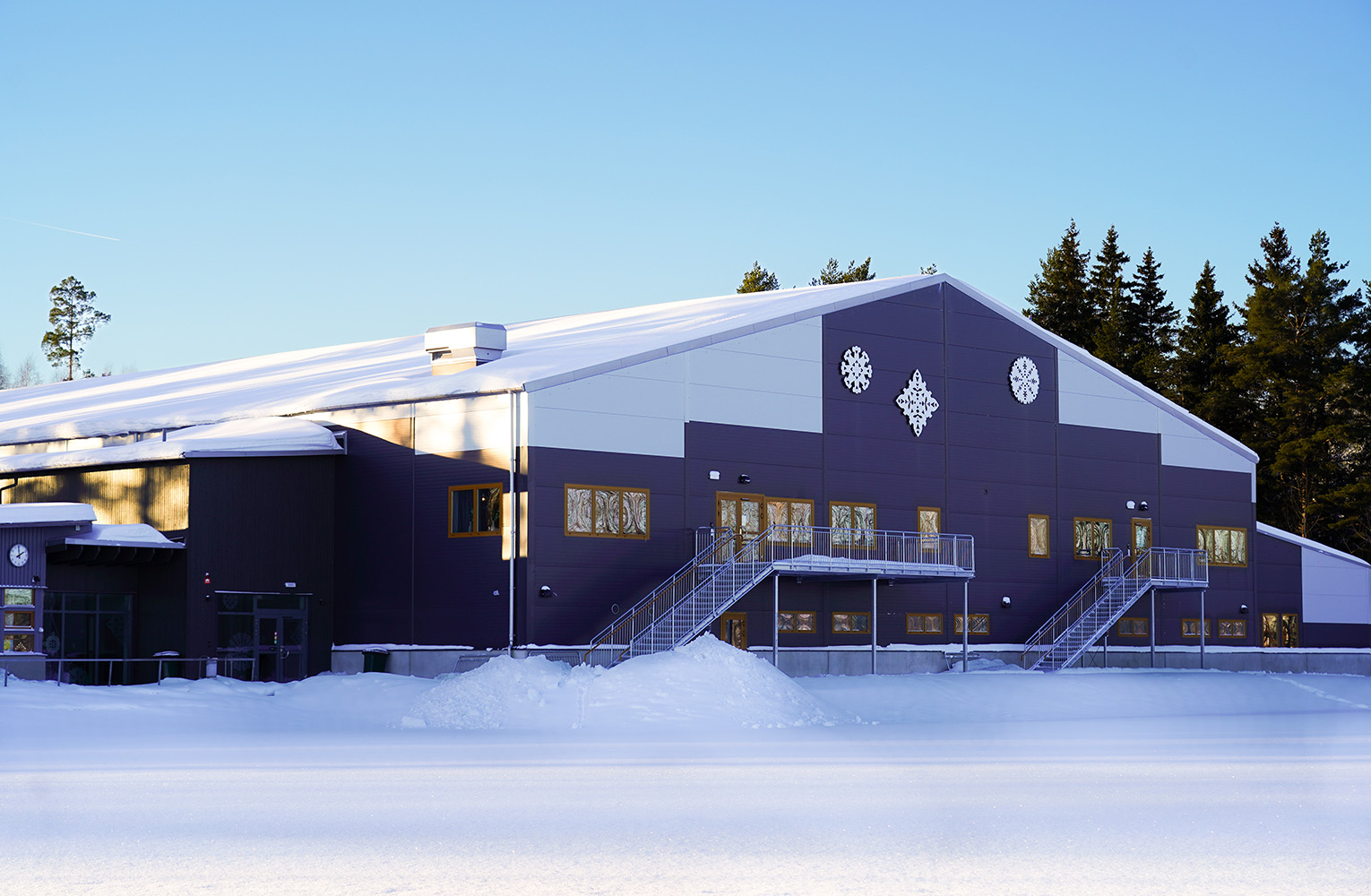 Gaveln på ett hus med mörka och ljusa partier på fasaden samt konstverk i form av snöstjärnor. Snötäckt mark.