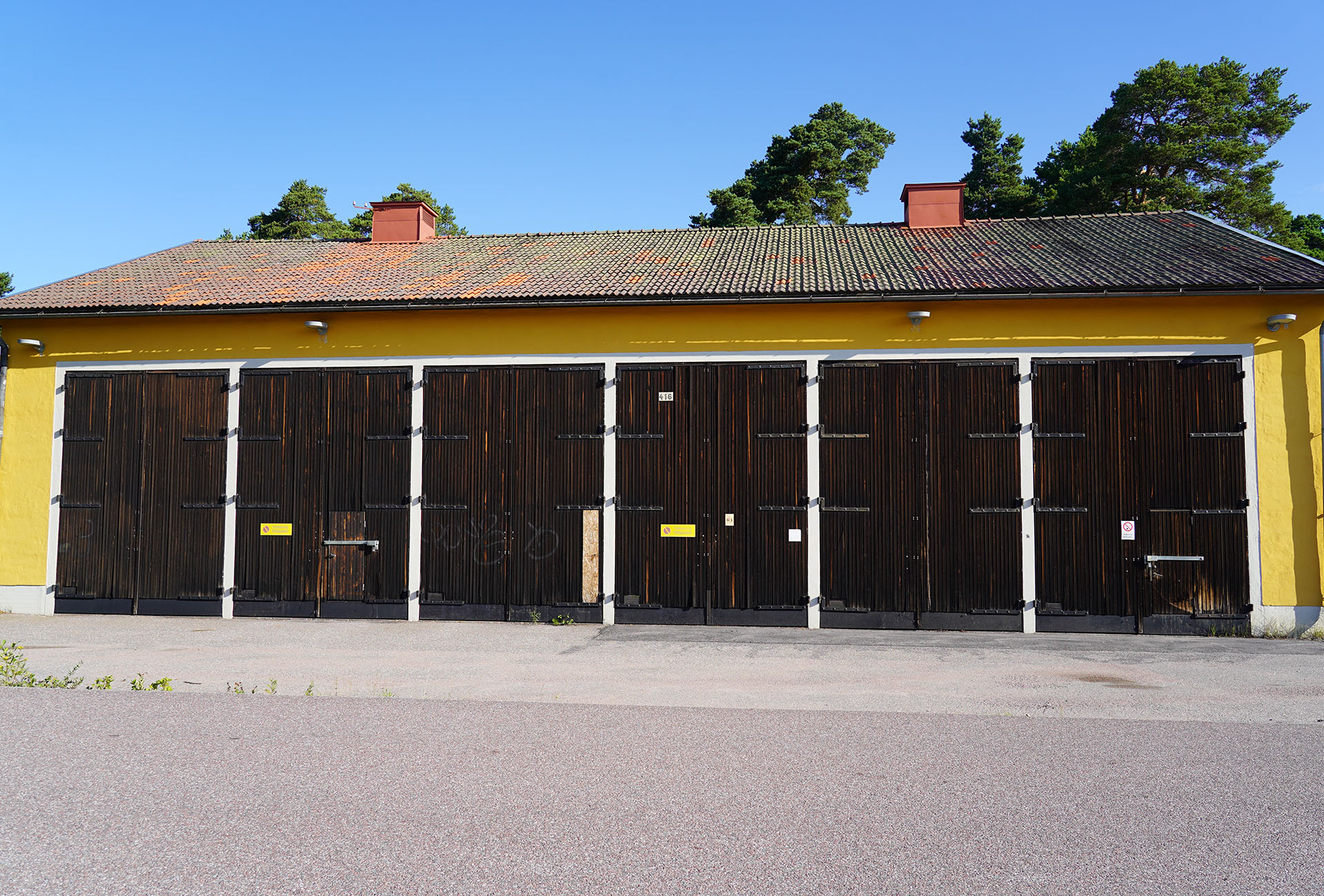 Sex bruna portar på långsidan av ett gult hus.