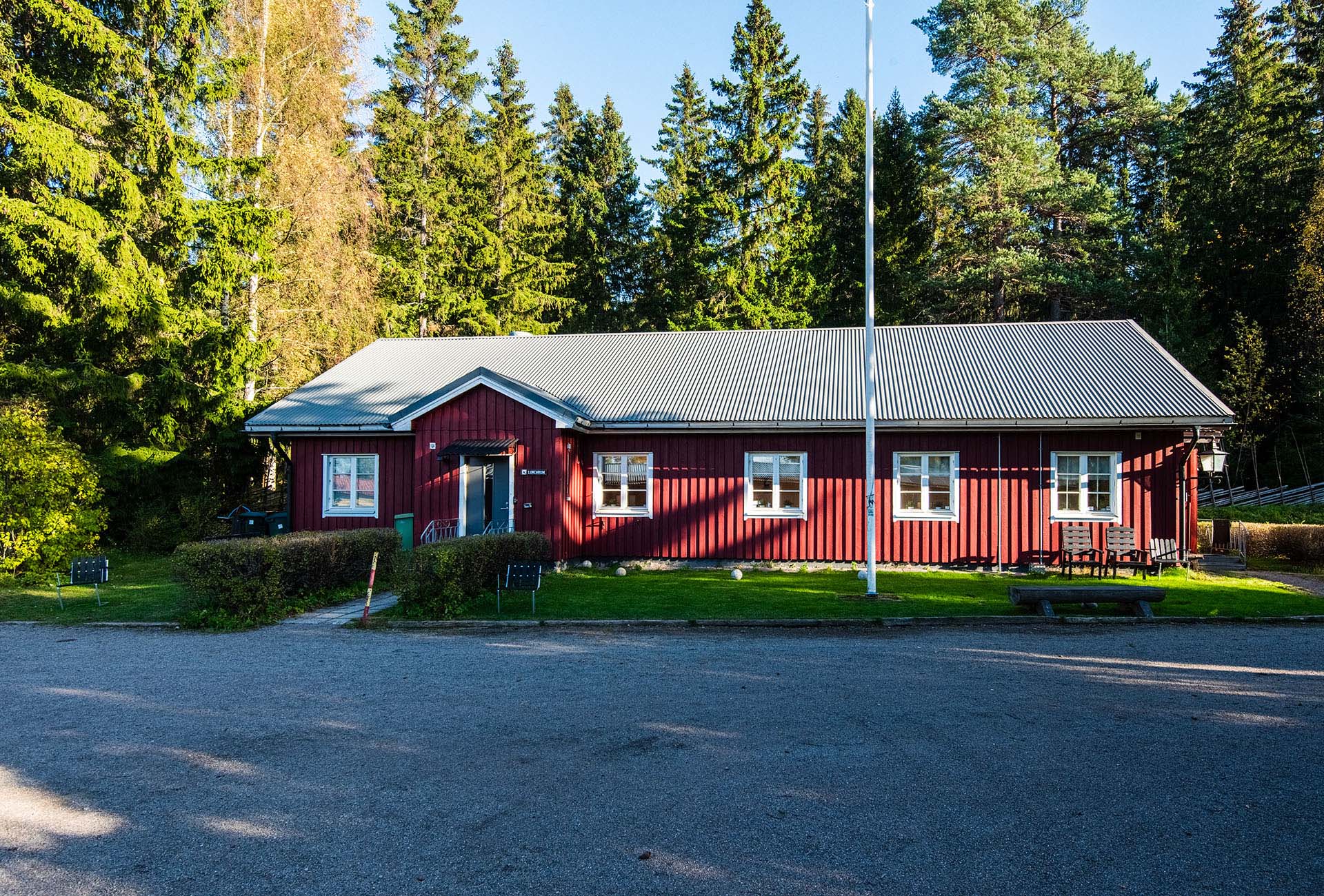 Rött trähus, ett plan med skog runt om.